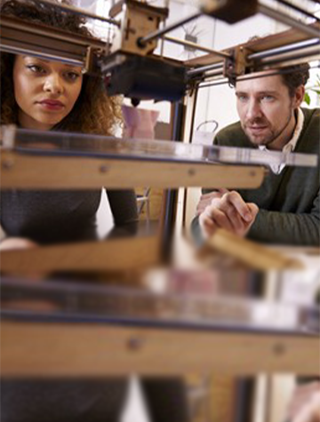 Woman and man look at 3D printer